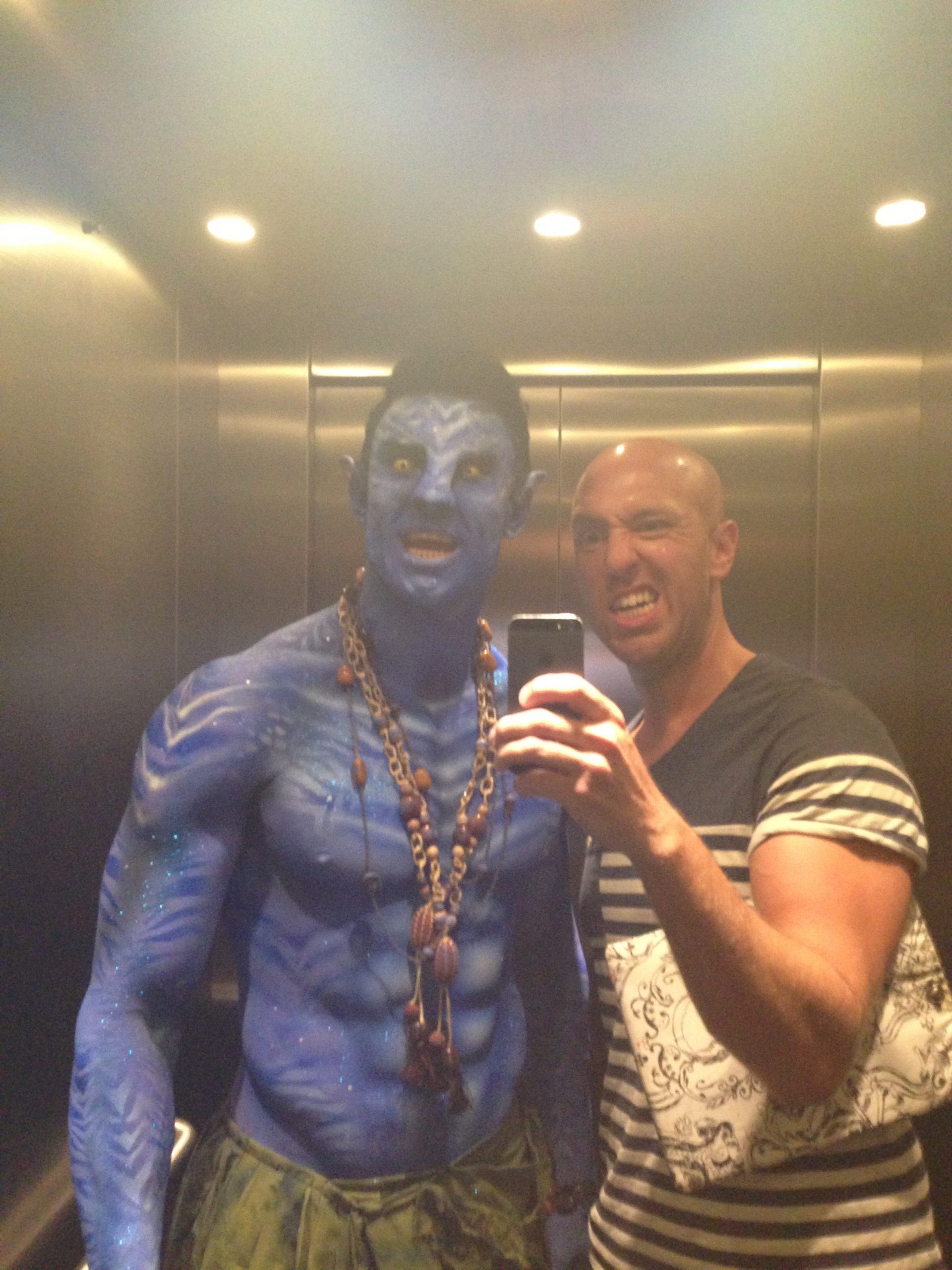 Neil Hughes body painter make-up artist in a lift with a male model body painted as blue avatar with prosthetics nose
