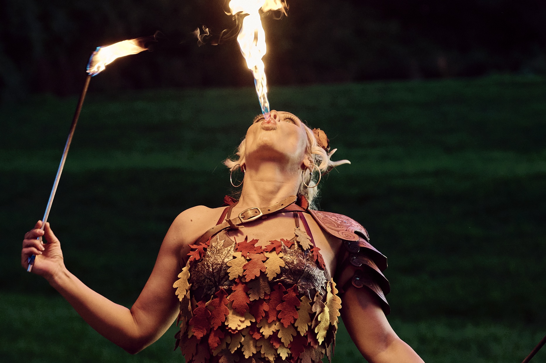 Bambi Fire Performer A female, fire circus performer, dressed as a faun in leaf costume at night, breathing fire