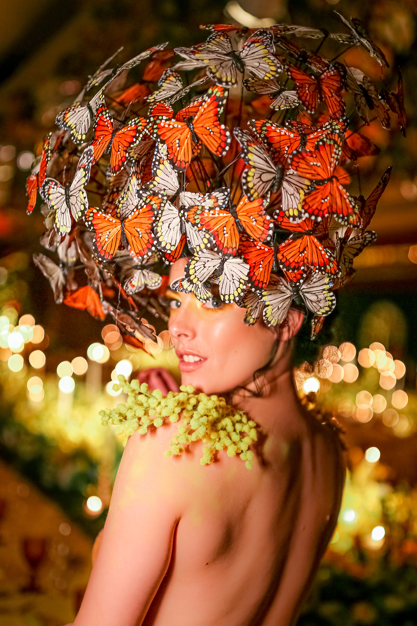 Butterfly beauty A woman dressed with a large headdress of fluttering butterflies looks over her shoulder covered in body art