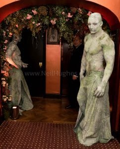 Body painted statue of a muscular model painted with moss and body paint