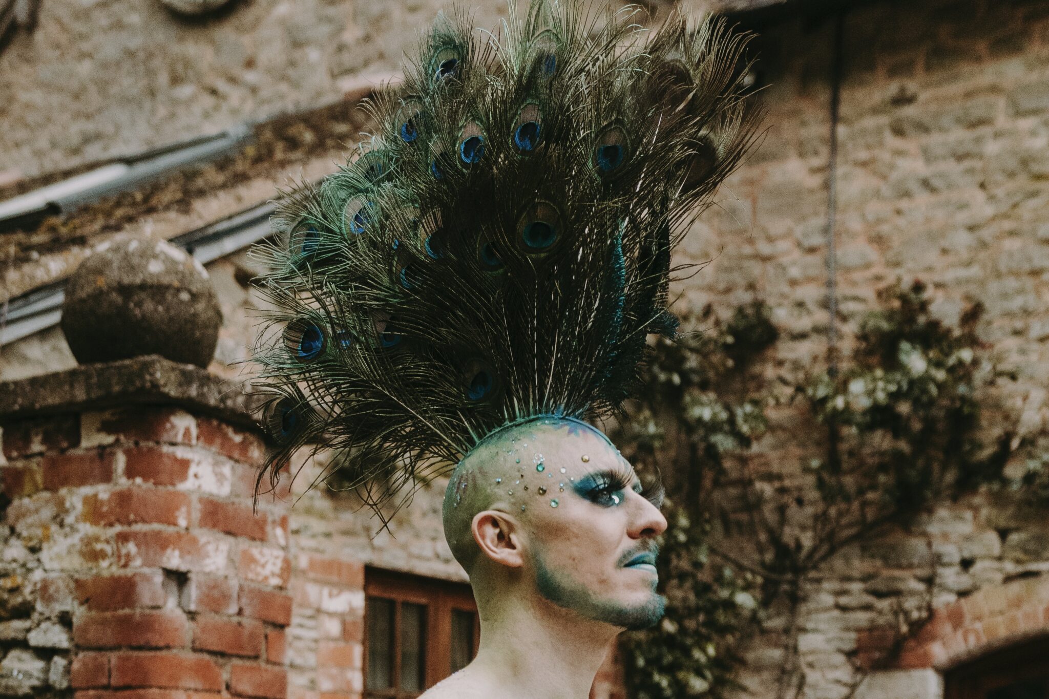 Peacock Cockscomb A man with a peacock feather mohawk and body art at a enchanted garden party